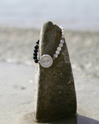 Bracelet with face charm on a stone by the beach