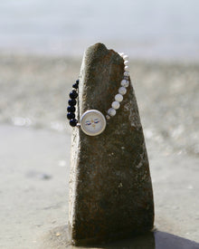 Bracelet with face charm on a stone by the beach
