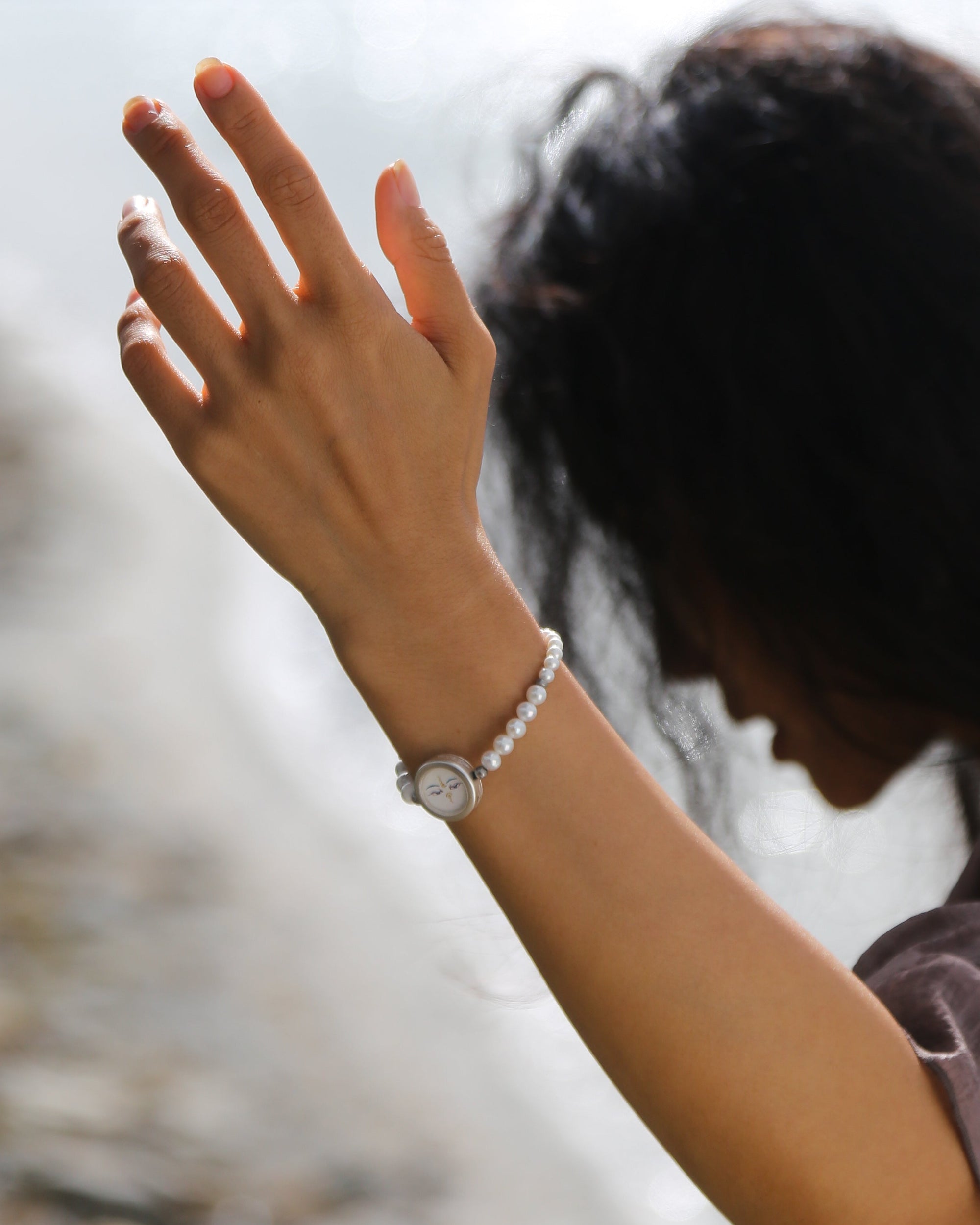 Person wearing a bracelet with a blurred natural background